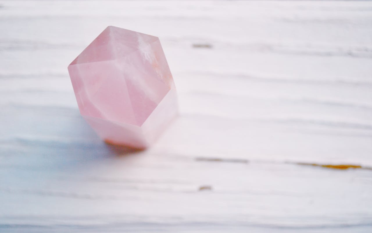 A pastel pink crystal with a soft focus on a textured surface, perfect for meditation themes.